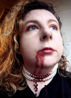 photo of morgan (that's me!) with fake blood on the mouth and chin and a fake pearl necklace made to look like there's blood on it